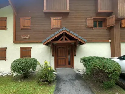 a house with a wooden door and some bushes at Les Carlines in Les Contamines-Montjoie