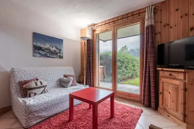 a living room with a couch and a table and a window at Les Carlines in Les Contamines-Montjoie