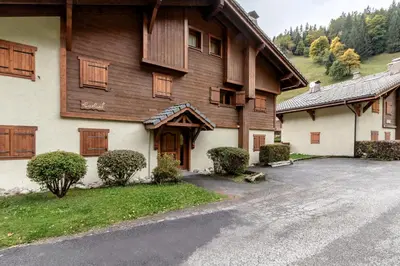 a large wooden house with a driveway in front of it at Les Carlines in Les Contamines-Montjoie