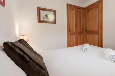 a bedroom with two white beds and a wooden door at Les Carlines in Les Contamines-Montjoie