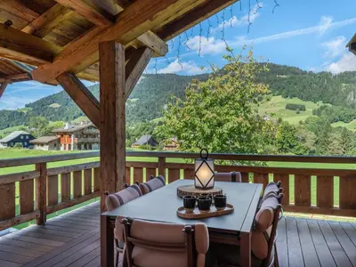 a table and chairs on a deck with a view at Chalet d'Exception à Megève avec Piscine et Cinéma - FR-1-569-194 in Megève