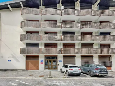 two cars parked in a parking lot in front of a building at CL124 Studio cabine cosy 4 pers centre in Les Carroz d'Araches