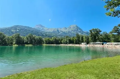 a lake with a beach and mountains in the background at Résidence Vallée Blanche in Sallanches