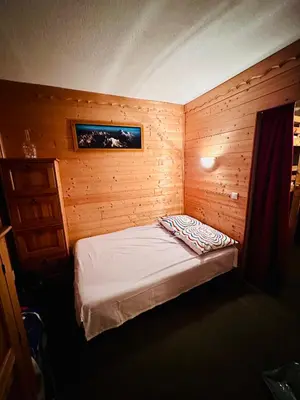 a small bedroom with a bed in a wooden room at Studio vue montagne à 200m des pistes in Arâches-la-Frasse