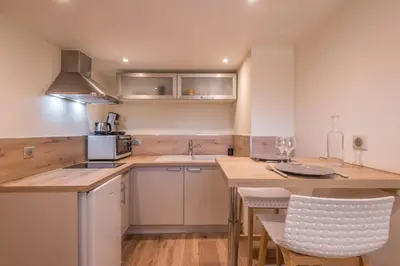a kitchen with white cabinets and a wooden counter top at Appartement Couttet - Welkeys in Chamonix-Mont-Blanc