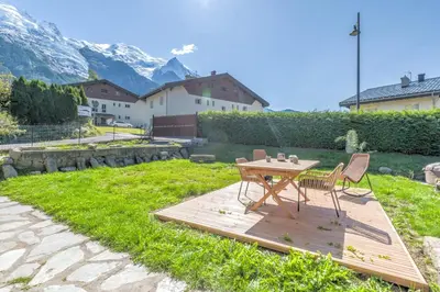 a wooden table and chairs in a yard with mountains at Appartement Couttet - Welkeys in Chamonix-Mont-Blanc