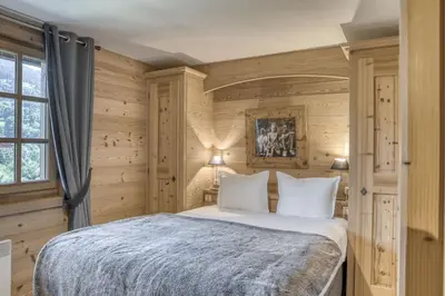 a bedroom with a large bed with wooden walls at Harmonie in Demi-Quartier