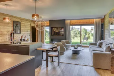 a kitchen and living room with a couch and a table at Charmant Appartement au Cœur de Megève avec Jardin privatif in Megève