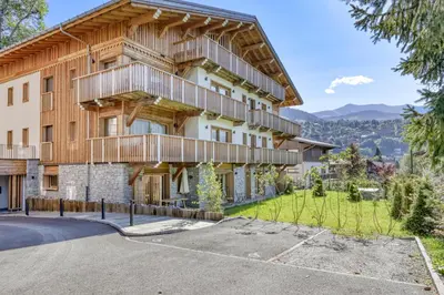 an apartment building with a balcony and a driveway at Charmant Appartement au Cœur de Megève avec Jardin privatif in Megève