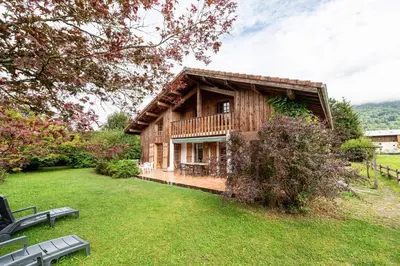 a log cabin with a deck in a yard at Chalet Cleo - charmant chalet 180 m2 avec vue montagne in Samoëns