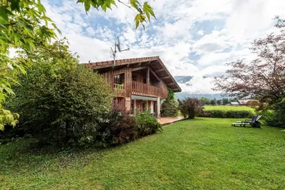 a log house with a grassy yard in front of it at Chalet Cleo - charmant chalet 180 m2 avec vue montagne in Samoëns