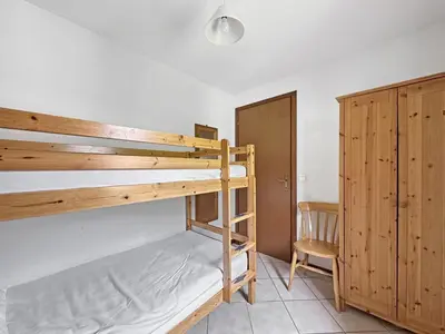 a bedroom with two bunk beds and a chair at SC316 - Duplex 8 Pers centre des Carroz in Les Carroz d'Araches