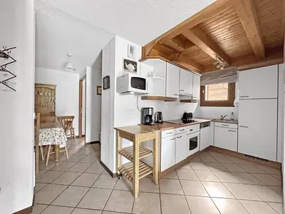 a kitchen with white cabinets and a table in it at SC316 - Duplex 8 Pers centre des Carroz in Les Carroz d'Araches