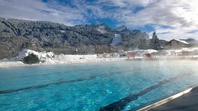 a pool of water with snow and mountains in the background at AT101 Appartement 6 Pers proche base de loisirs in Les Carroz d'Araches