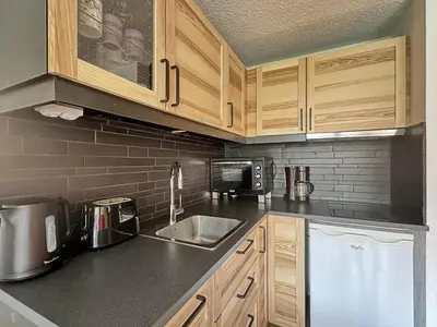 a kitchen with wooden cabinets and a sink at CAL02 - Studio 4 Pers centre des Carroz in Les Carroz d'Araches