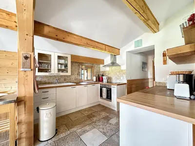 a kitchen with white cabinets and wooden beams at CH136 - Chalet Kimberley Centre village les Carroz in Les Carroz d'Araches