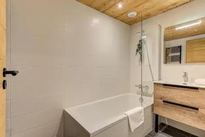 a white bathroom with a tub and a sink at Apartment des Alpages - Alpes Travel - Sleeps 6-8 in Les Trabets