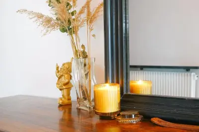 a mirror with two candles and a vase with flowers at Maison de montagne in Passy