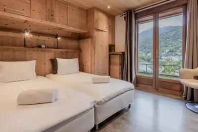 two beds in a room with a large window at Le Covagnet in Saint-Gervais-les-Bains