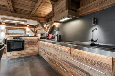 a kitchen with wooden cabinets and a large sink at Le Covagnet in Saint-Gervais-les-Bains