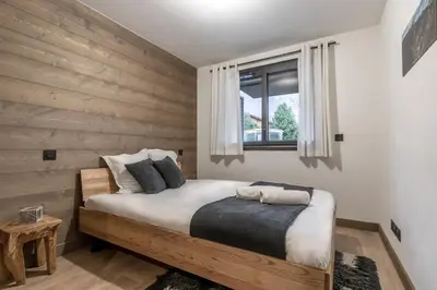 a bedroom with a wooden accent wall and a bed at Cristal Des Alpes - Superb T3 - Vue Mont-Blanc in Les Houches