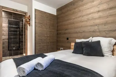 a bedroom with a large white bed and a wooden wall at Cristal Des Alpes - Superb T3 - Vue Mont-Blanc in Les Houches