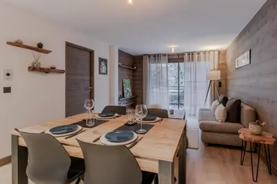 a dining room and living room with a wooden table and chairs at Cristal Des Alpes - Superb T3 - Vue Mont-Blanc in Les Houches