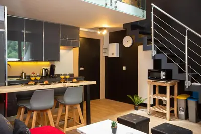 a kitchen with black cabinets and a counter with chairs at Les Barrats - Duplex - Central - Vue Mont-Blanc in Chamonix-Mont-Blanc