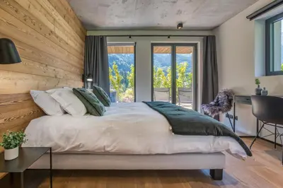 a bedroom with a large bed with a desk and windows at Chalet Choucas - Modern Luxury - Heart of Chamonix in Chamonix-Mont-Blanc