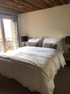 a bedroom with a large white bed with a window at Chalet Aspre in Samoëns