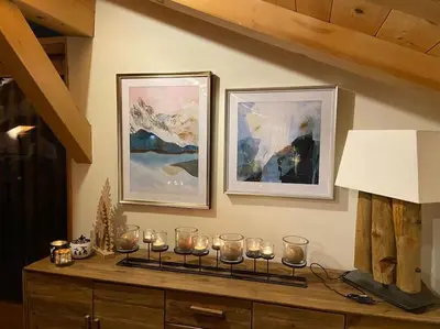 a room with candles on a dresser with paintings at Chalet Aspre in Samoëns