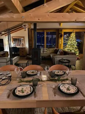 a table with plates and wine glasses and a christmas tree at Chalet Aspre in Samoëns