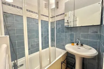 a blue tiled bathroom with a sink and a shower at Terrasse du Front de Neige in Demi-Quartier
