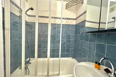 a blue tiled bathroom with a tub and a sink at Terrasse du Front de Neige in Demi-Quartier