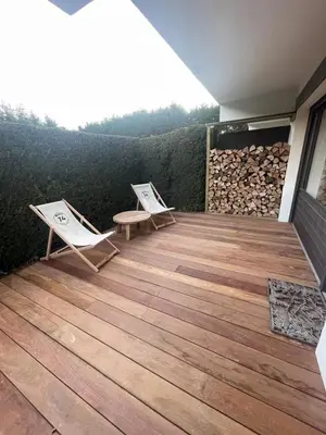 a deck with two chairs and a bench on it at Appartement chaleureux à Megève - 80 m² avec jardin et cheminée. in Megève