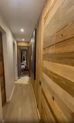 a hallway with a wall of wood paneling at Appartement chaleureux à Megève - 80 m² avec jardin et cheminée. in Megève