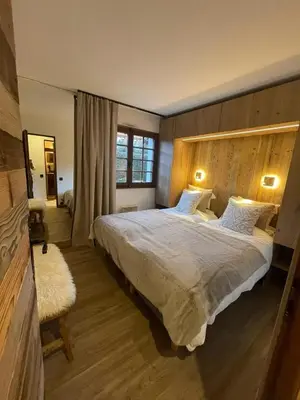 a bedroom with a large bed with a wooden headboard at Appartement chaleureux à Megève - 80 m² avec jardin et cheminée. in Megève
