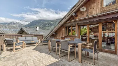a wooden house with a table and chairs on a patio at Ferme des Moussoux in Chamonix-Mont-Blanc