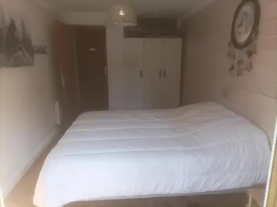 a white bed in a bedroom with a clock on the wall at Appartement à la Montagne in Saint-Gervais-les-Bains
