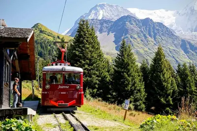 a red train on the tracks with a mountain at Appartement à la Montagne in Saint-Gervais-les-Bains