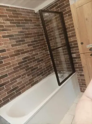 a bathroom with a bath tub with a brick wall at Appartement à la Montagne in Saint-Gervais-les-Bains