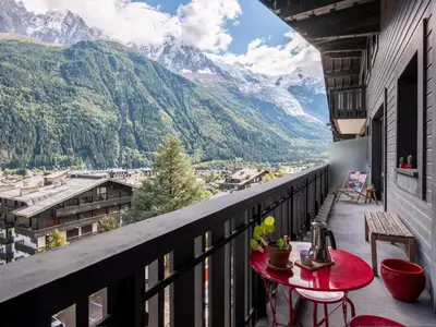 a balcony with a table and a view of mountains at Appt Laltimetre - Jardin - Skis aux pieds in Chamonix-Mont-Blanc