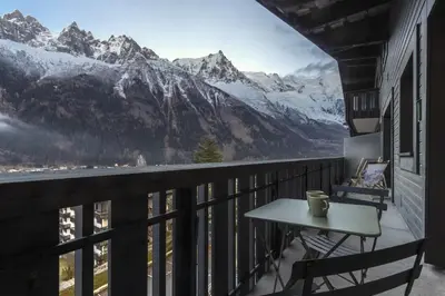 a balcony with a table and a view of mountains at Appt Laltimetre - Jardin - Skis aux pieds in Chamonix-Mont-Blanc