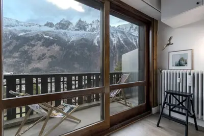 a room with a balcony with a view of mountains at Appt Laltimetre - Jardin - Skis aux pieds in Chamonix-Mont-Blanc