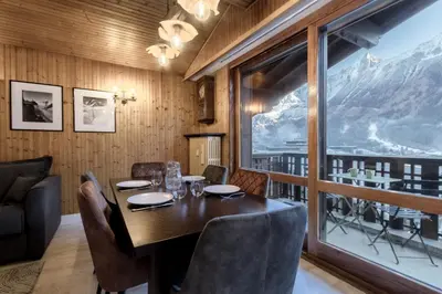 a dining room with a table and a view of a mountain at Appt Laltimetre - Jardin - Skis aux pieds in Chamonix-Mont-Blanc