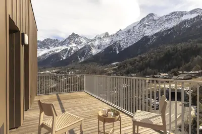 a balcony with chairs and a table and mountains at Apartment Léo -Espace bien-être -Piscine in Les Houches