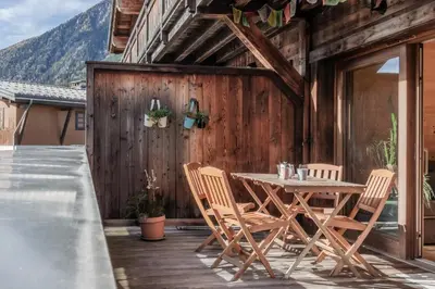 a wooden patio with a table and chairs on a deck at Grand Paradis in Chamonix-Mont-Blanc