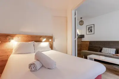 a bedroom with a white bed and a living room at Grepon Paradis - Chamonix - Proche Aiguille Midi in Chamonix-Mont-Blanc