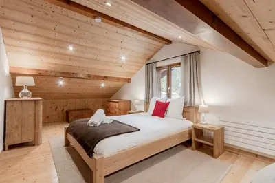 a bedroom with a bed in a room with wooden walls at La Bastide - Grand chalet privé - Quartier calme in Les Houches