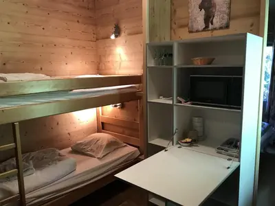 a room with bunk beds with a desk and a tv at La Ferme du Lay in Arâches-la-Frasse